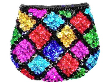 Puede incluir: Un pequeño bolso de mano con cuentas, con un borde negro y un patrón geométrico colorido. El patrón presenta cuadrados de cuentas rojas, amarillas, verdes, azules y moradas. El bolso es probablemente vintage o hecho a mano.