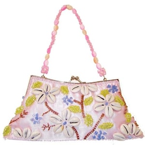 May include: A pale pink handbag with a beaded handle. The bag is adorned with white seashell flowers, green leaves, and blue accents. The handle is made of pink and peach-coloured beads.