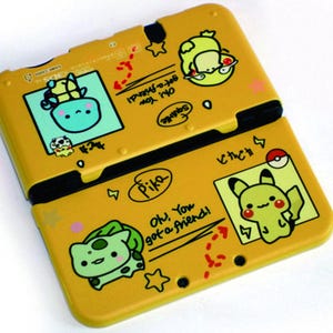 Könnte beinhalten: Eine gelbe Hülle für eine tragbare Spielkonsole mit Cartoon-Illustrationen von Pokemon-Charakteren wie Pikachu, Bisasam und Schiggy. Die Hülle enthält den Text "Oh, You got a friend!" sowie kleine Stern- und Blitzgrafiken.