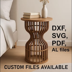 Puede incluir: Una mesa auxiliar de madera marrón con una base en forma de reloj de arena. La mesa tiene una tapa redonda con dos libros y un jarrón blanco con flores secas. El texto "DXF, SVG, PDF, AL files" y "CUSTOM FILES AVAILABLE" es visible.