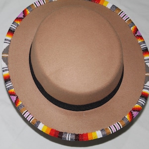 Puede incluir: Un sombrero fedora color canela con una banda negra y un ribete de cuentas. El ribete presenta un patr&oacute;n colorido de cuentas rojas, amarillas, blancas y moradas. El sombrero tiene un ala ancha.