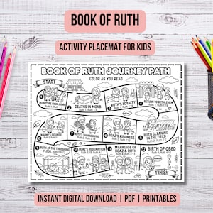 May include: A black and white activity placemat for kids with the text "Book of Ruth Journey Path." The placemat features a path with illustrations and text, including "Start" and "Finish." Colored pencils are in a black metal container and scattered on a wooden surface.