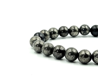 May include: A bracelet featuring spherical beads with a metallic, speckled appearance. The beads are primarily dark gray with hints of silver, strung together to form a circular shape. The bracelet is set against a white background.