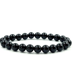 May include: A black beaded bracelet. The bracelet is made of polished, round, black beads strung together on an elastic band. The beads have a glossy finish and reflect light. The bracelet is displayed on a white background.