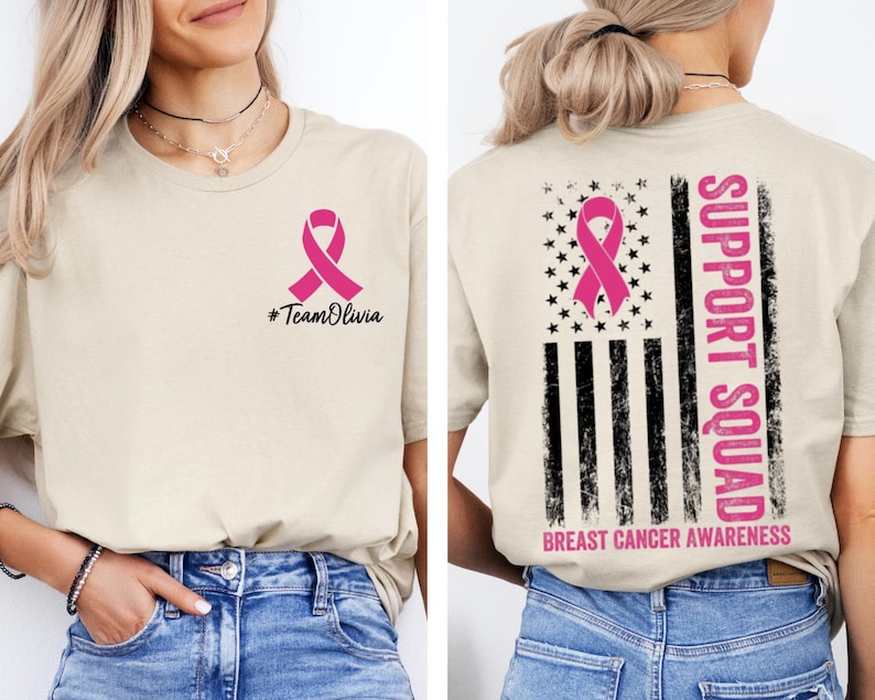 May include: Beige t-shirt with a pink ribbon graphic and the text "#TeamOlivia" on the front. The back of the shirt features a pink ribbon, stars, and stripes design with the words "SUPPORT SQUAD" and "BREAST CANCER AWARENESS".