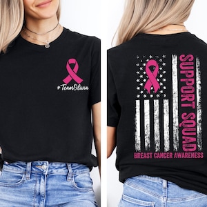 May include: Black t-shirt with a pink ribbon and the text "#TeamOlivia" on the front. The back features a pink ribbon design within a distressed American flag, with "SUPPORT SQUAD" and "BREAST CANCER AWARENESS" text.