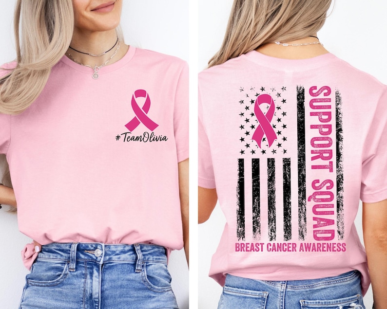 May include: Pink t-shirt with a pink ribbon graphic and the text "#TeamOlivia" on the front. The back features a pink ribbon, stars, stripes, and the words "Support Squad" and "Breast Cancer Awareness".