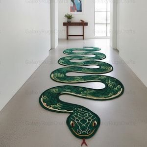 May include: A green snake-shaped rug with a detailed head and body, placed on a grey floor. The rug features a textured design with yellow and white accents, creating a realistic appearance. The snake's head is at the bottom, with a red tongue.