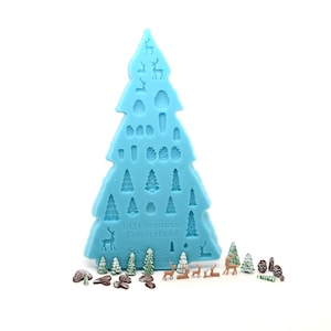 May include: A blue silicone mould shaped like a Christmas tree with 12 different designs for making miniature Christmas trees, reindeer, and pine cones. The mould is labelled "12 Christmas Forest Mould". There are also several miniature Christmas trees, reindeer, and pine cones made with the mould.