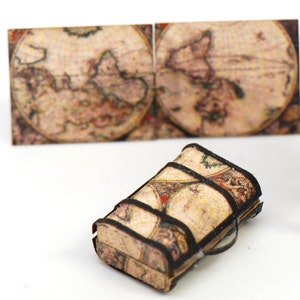 May include: A small, vintage-style suitcase with a brown and black design. The suitcase is covered in a map-like pattern.