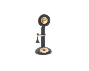 May include: Black vintage-style rotary phone with a gold-colored dial and a black receiver. The phone is on a black base.