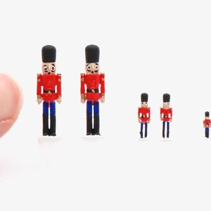 以下が含まれることがあります： さまざまなサイズのミニチュアくるみ割り人形が5体。くるみ割り人形は、赤色のコート、黒い帽子、白い顔という伝統的なデザインで、塗装された木で作られています。