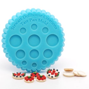 Puede incluir: Un molde de silicona azul para hacer tartas en miniatura. El molde tiene 10 moldes individuales para tartas y dice "Stewart Dollhouse Creations Tart Pan Mold". También hay varias tartas en miniatura con coberturas de frutas rojas y azules.