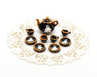 May include: A miniature black and orange Halloween tea set with a teapot and six cups and saucers. Each piece features a white ghost design.