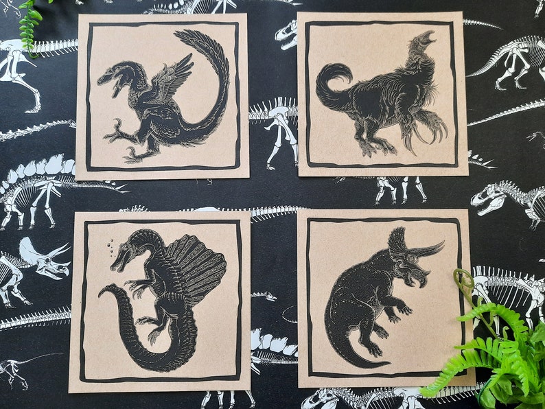May include: Set of five brown paper cards with black and white illustrations of dinosaurs. The illustrations include a Pterodactyl, a Triceratops, a Stegosaurus, a Tyrannosaurus Rex, and a Velociraptor.