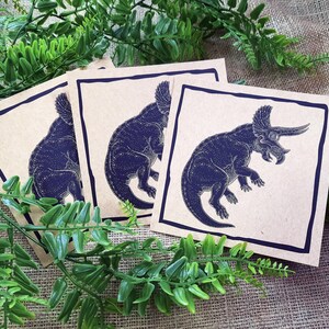 May include: Three brown paper cards with black outlines. Each card features a black silhouette of a triceratops dinosaur.