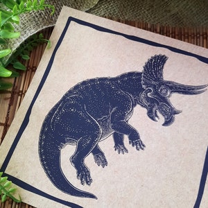 May include: A black and white illustration of a triceratops dinosaur on a brown paper background.
