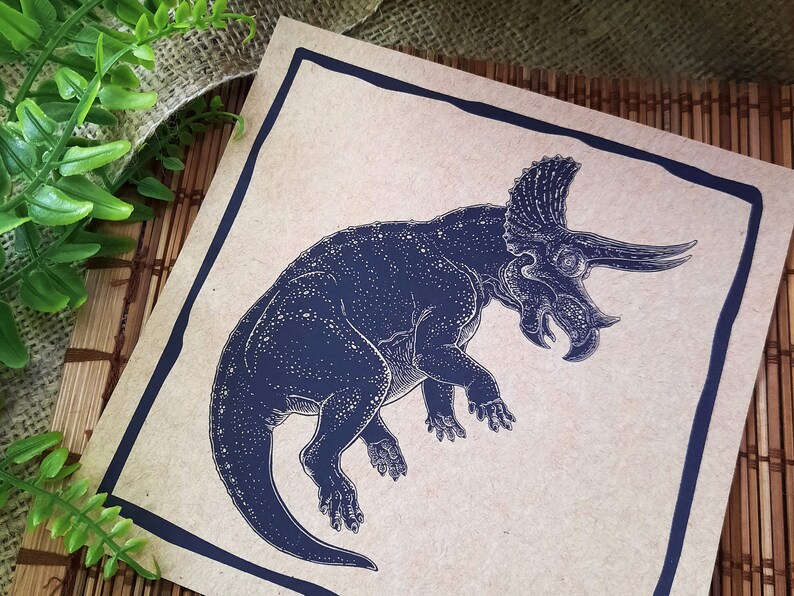 May include: A black and white illustration of a triceratops dinosaur on a brown paper background.