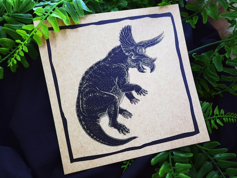 May include: A black and white illustration of a triceratops dinosaur on a brown paper background.