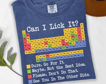 May include: Blue t-shirt with the text "Can I Lick It?" above a periodic table of elements. Below the table are the phrases "Sure, Go For It," "Maybe, Not the Best Idea," "Please, Don't Do That," and "See You In The Other Side."