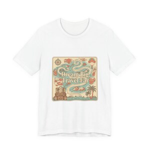 May include: White t-shirt featuring a colorful graphic with the text "Dream Big, Travel Far." The design includes a map with a compass, hot air balloon, palm tree, and luggage. The shirt is made of a soft, comfortable material.