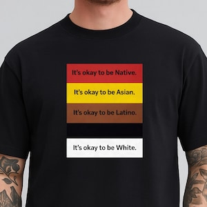 Può includere: T-shirt nero con la scritta "It's okay to be Native," "It's okay to be Asian," "It's okay to be Latino," e "It's okay to be White." Il testo è presentato su un design a blocchi di colore.