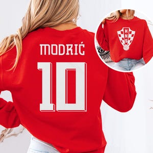 A woman wearing a red sports jersey with the number 10 on it.