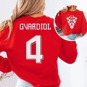 A woman wearing a red sports jersey with the number 4 and the name 'Guardiol' printed on it.