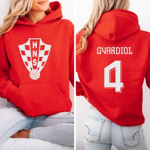 A woman wearing a red hoodie with a white logo and the number 4 on the back.