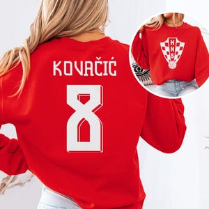 A woman wearing a red sweater with the number 8 and the name "Kovacic" printed on it.
