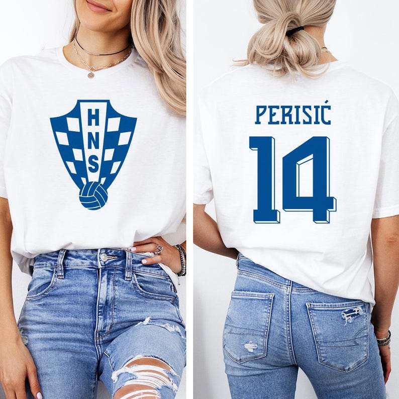 A woman wearing a white t-shirt with a blue logo and the number 14 on the back, paired with distressed blue jeans.