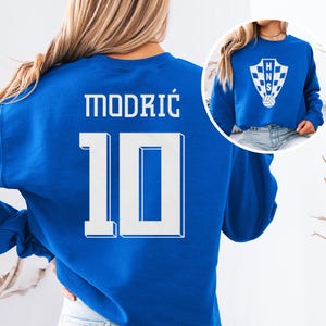 A woman wearing a blue sweatshirt with the number 10 and the name "Modric" printed on it.