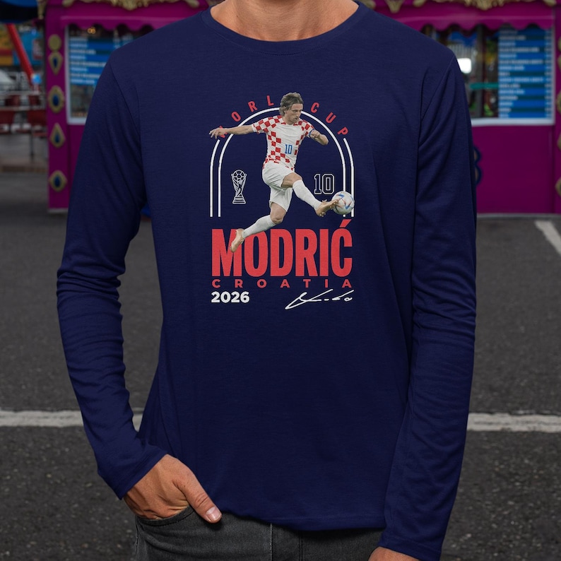 a man in a blue long-sleeved shirt with a graphic design depicting a soccer player in action.