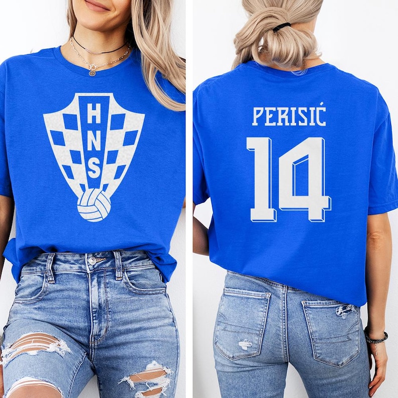 A woman wearing a blue t-shirt with a white logo and the number 14 on the back, paired with distressed jeans.