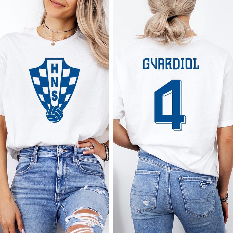 A woman wearing a white t-shirt with a blue shield logo and the number 4 on the back, paired with distressed blue jeans.