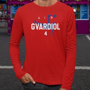 A man wearing a red long-sleeved shirt with the text "AIR GVARDIOL 4" printed on it.