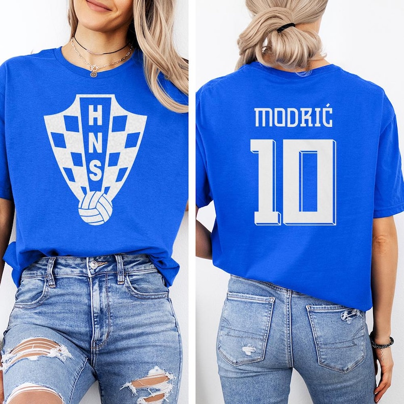 A woman wearing a blue t-shirt with a white logo and the number 10 on the back, paired with distressed jeans.