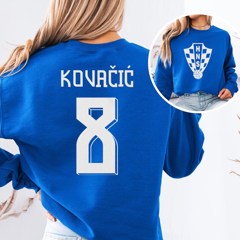 A woman wearing a blue sweatshirt with the number 8 and the name "KOVACIÓ" printed on it.