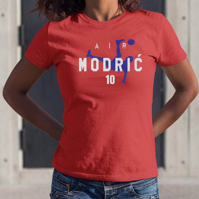 A woman wearing a red t-shirt with the text "AIR MODRIC 10" printed on it.