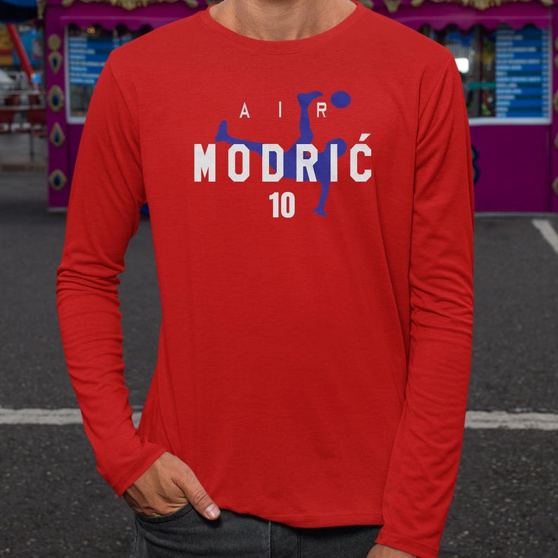 A man wearing a red long-sleeved shirt with the text "AIR MODRIC 10" printed on it.