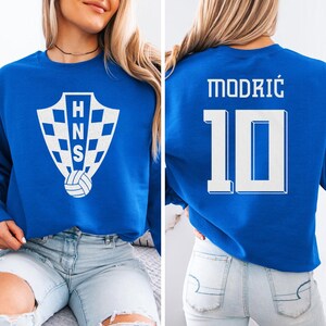 A woman wearing a blue sweatshirt with a white crest and the number 10 on the back.
