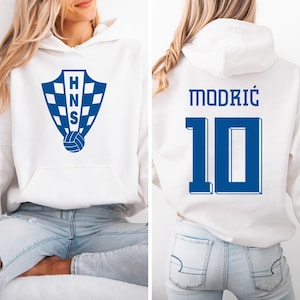 A white hoodie with a blue logo and the number 10 on the back, along with the name 'MODRIC' and the number '10'.