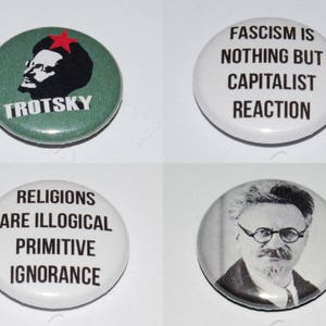 May include: Four circular badges with political slogans and portraits. One badge shows a portrait of Trotsky with the word "TROTSKY". Another says "FASCISM IS NOTHING BUT CAPITALIST REACTION". A third says "RELIGIONS ARE ILLOGICAL PRIMITIVE IGNORANCE". The last badge has a portrait of a man.