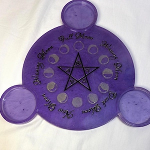 May include: A purple circular tray with three smaller circular attachments, featuring a central black pentagram symbol surrounded by small moon phase icons and text labels including Full Moon, Waning Moon, Dark Moon, and New Moon in black script.