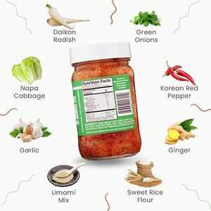May include: A glass jar of kimchi with a white lid, surrounded by ingredients including Napa cabbage, daikon radish, green onions, and Korean red pepper. The label displays nutrition information. Other ingredients include garlic and ginger.