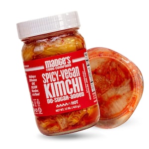 May include: A jar of Madge's Food Company Spicy-Vegan Kimchi with a white lid and a red label. The label indicates the product is no-sugar-added and hot. The net weight is 15 oz (425 g). A container of kimchi is next to the jar.