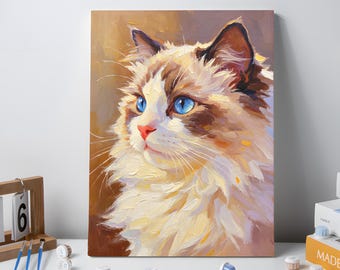May include: A canvas print of a Ragdoll cat with striking blue eyes and a fluffy, cream-colored coat with brown markings. The painting is displayed on a white surface with paint supplies and books.