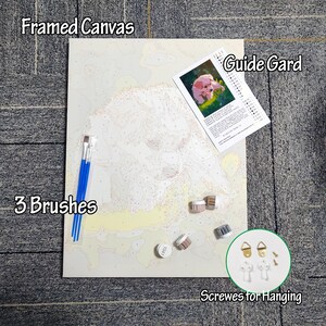 May include: A paint-by-numbers kit featuring a framed canvas with a dog outline, three blue-handled paint brushes, small paint pots, a guide card, and screws for hanging. The canvas is labeled "Framed Canvas".