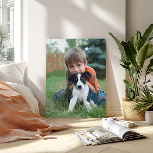 May include: A rectangular canvas print featuring a stylized illustration of a young child with light brown hair wearing an orange shirt, embracing a black and white puppy with a white blaze on its face, set against a green grassy outdoor background.