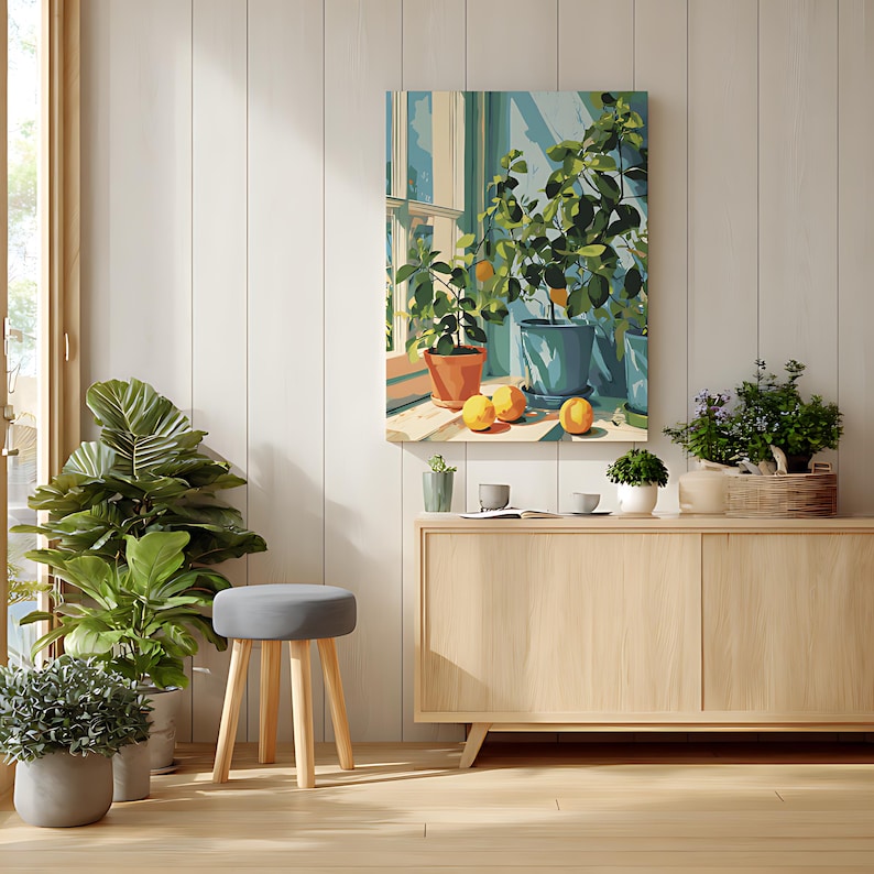 May include: A light-filled interior scene featuring a painting of potted plants and lemons on a windowsill. A gray stool with wooden legs sits in front of a wooden cabinet. Several potted plants are visible, including a large fiddle-leaf fig.